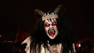 Krampusfigur mit Hörnern, geschmückter Krone und grimmiger Maske bei Nacht