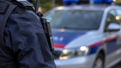 Nahaufnahme einer uniformierten Polizeikraft vor einem unscharfen Streifenwagen.