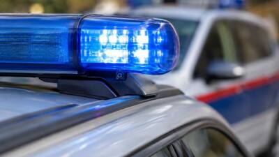KI-Symbolbild: Blaues Warnlicht auf dem Dach eines silbernen Autos mit rot-blauer Seitenmarkierung.