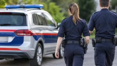 Zwei uniformierte Polizeikräfte gehen neben einem Streifenwagen mit Blaulicht.