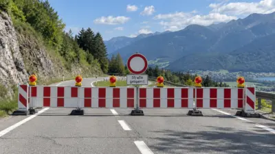Rot-weiße Absperrung mit Sperrschild vor einer alpinen Berglandschaft