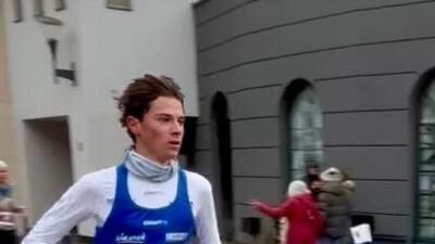 Läufer mit blauem Trikot und Startnummer 142 läuft über eine Straße.