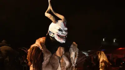Krampusfigur mit langer Hörnermaske und Fellkostüm bei Nacht