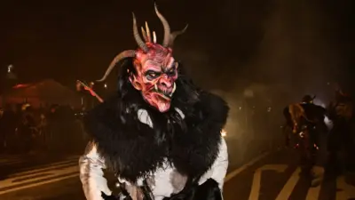 Ein Krampus mit Hörnermaske und schwarzem Fell steht nachts auf einer Straße.