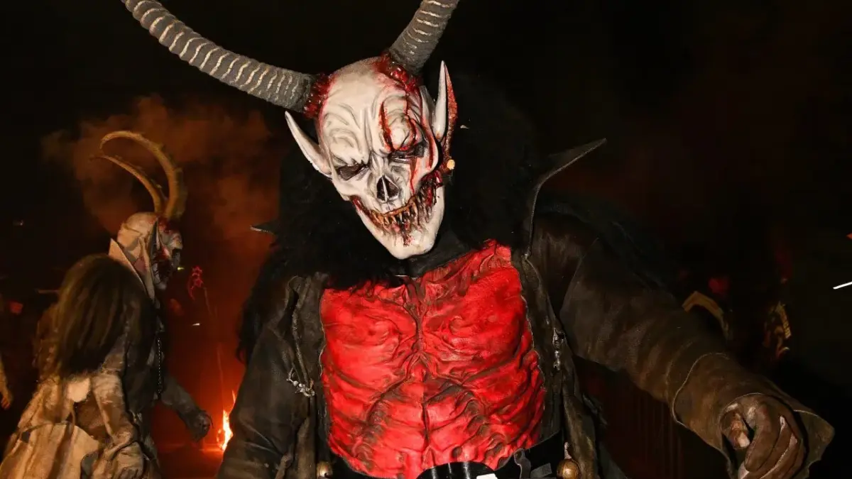 Krampus mit großer Hörnermaske und rotem Kostüm bei einem nächtlichen Lauf