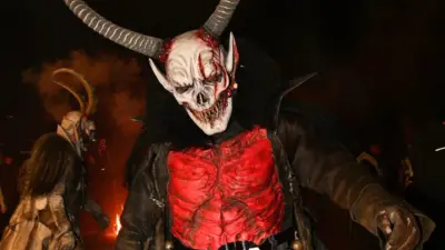 Krampus mit großer Hörnermaske und rotem Kostüm bei einem nächtlichen Lauf