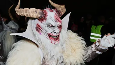Eine Person im zotteligen Krampus-Kostüm mit Hörnern und weiß-roter Maske.