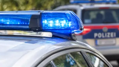 Blauer Blaulichtbalken auf einem Polizeiauto, dahinter ein unscharfes Polizeifahrzeug.