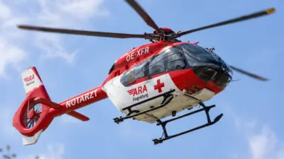 Rot-weißer Notarzthubschrauber fliegt vor blauem Himmel