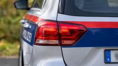 Nahaufnahme des Hecks eines österreichischen Polizeiwagens mit roten Rückleuchten.