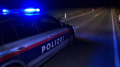 Ein Polizeiauto mit blauem Blinklicht steht nachts neben einer freien Straße.