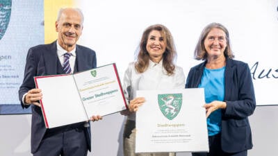 Drei Personen präsentieren Urkunden zur dauerhaften Führung des Grazer Stadtwappens.