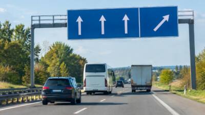 Verkehr auf einer Autobahn unter einem blauen Fahrspurhinweisschild