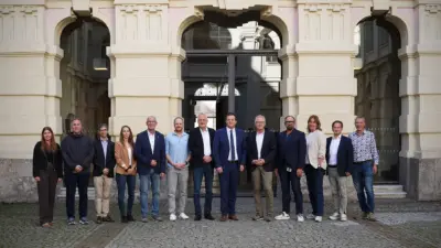 Eine Gruppe von Vertreterinnen und Vertretern steht vor einem reich verzierten Gebäude.