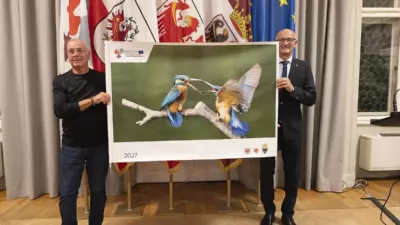Zwei Männer zeigen bei der Präsentation in Innsbruck das Titelmotiv des Euregio-Kalenders 2027 mit zwei Vögeln.