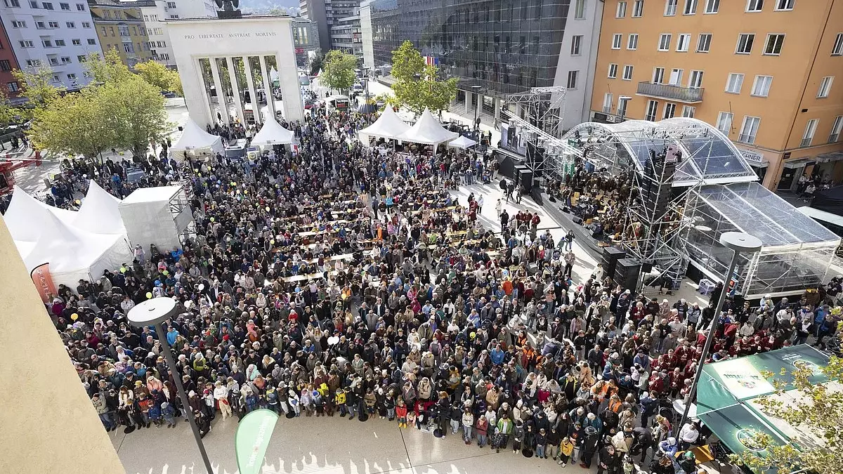 Besucher versammeln sich beim Tag der offenen Tür in Innsbruck auf einem Platz vor Zelten und einer Bühne.