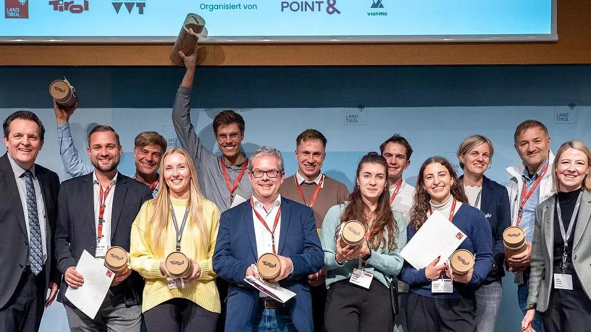Teilnehmende zeigen bei der Präsentation von Ideen zur Tourismusmobilität in Innsbruck Urkunden und Auszeichnungen.