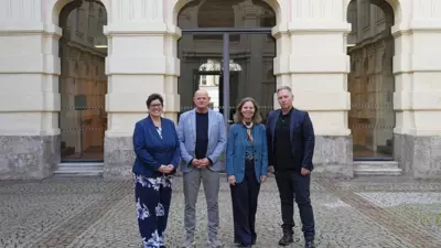 Vier Personen stehen vor dem Eingang eines reich verzierten Gebäudes.