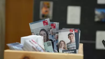 In einer Holzbox stehen Broschüren mit dem Land-Tirol-Logo und Porträtfotos.
