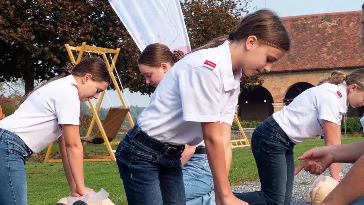 Jugendliche üben draußen die Herzdruckmassage an Wiederbelebungspuppen.