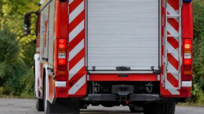 Rückansicht eines roten Feuerwehrfahrzeugs mit geschlossener Geräteraumklappe und Leiter