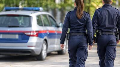 Uniformierte Polizeikräfte gehen auf ein geparktes Polizeiauto zu.