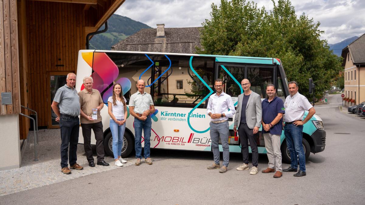 Menschen stehen vor einem bunt gestalteten Kleinbus der Kärntner Linien.
