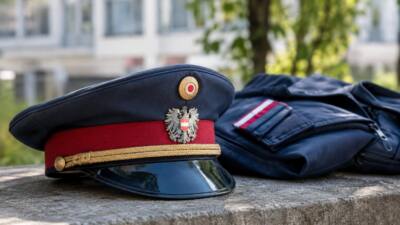 Polizeimütze und dunkelblaue Uniform liegen auf einer Steinmauer.