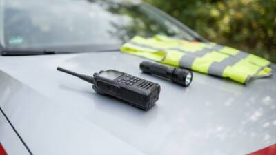 Funkgerät, Taschenlampe und Warnweste auf dem Dach eines Polizeiautos