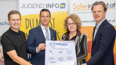 Erwachsene präsentieren ein Plakat der Initiative „Medienfit in Niederösterreich“ zum Umgang mit digitalen Medien.