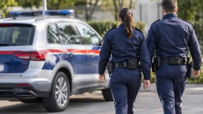 Uniformierte Personen gehen neben einem blau-weißen Fahrzeug mit Blaulichtbalken.