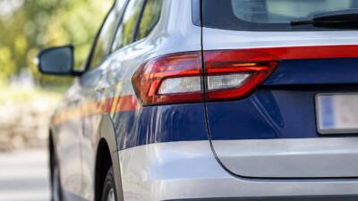 Nahaufnahme des Hecks eines blau-weißen Autos mit rot-gelber Seitenmarkierung