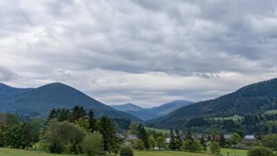 Dichte graue Wolken über bewaldeten Bergen und einem grünen Tal