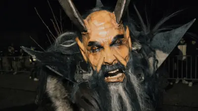 Nahaufnahme einer Krampusfigur mit Hörnern, dunklem Fell und furchterregender Maske