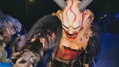 Eine Krampusfigur mit großer Hörnermaske und Fellkostüm bei einer nächtlichen Veranstaltung.